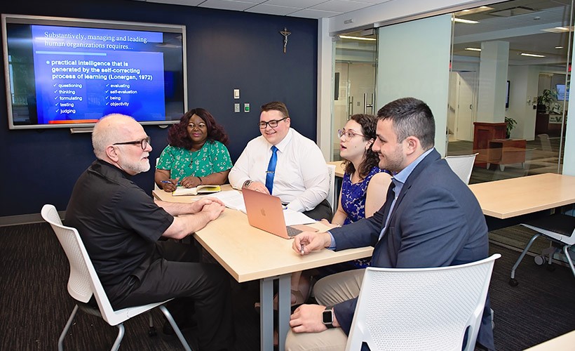 Graduate students sit around a table with a professor.