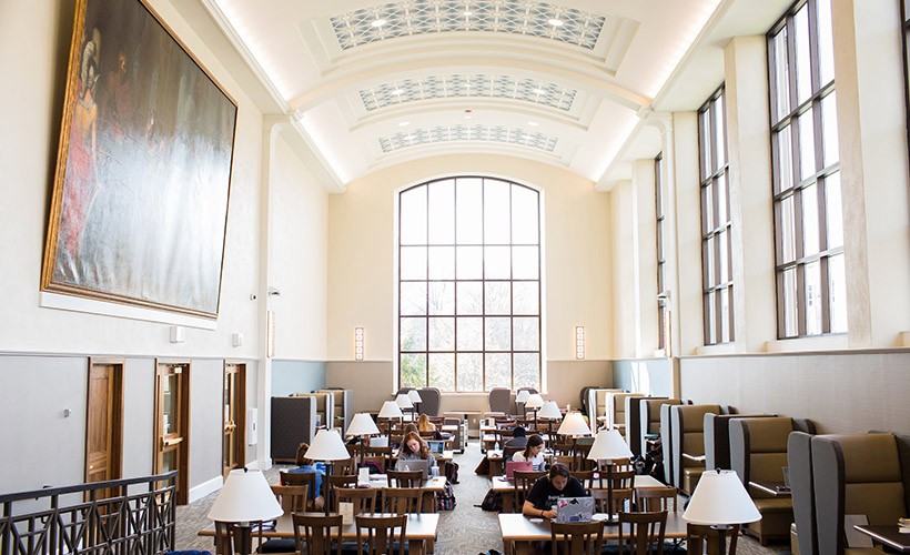 Students sit working at tables lined up in the Villanova library reading room.