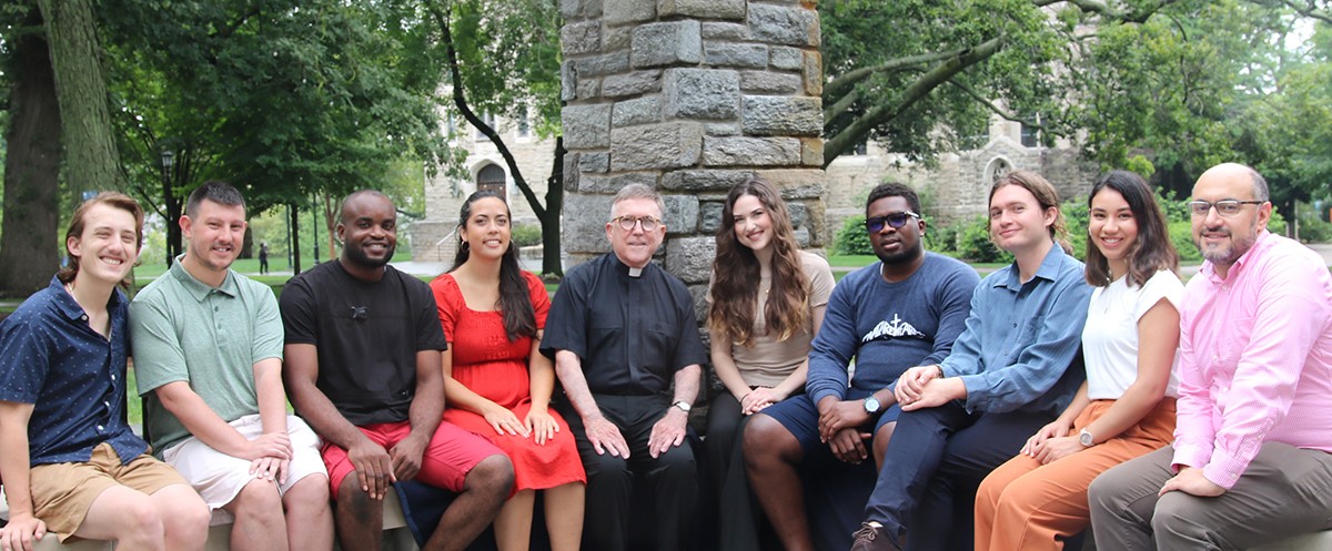 graduate theology students and faculty sitting outside on a ledge