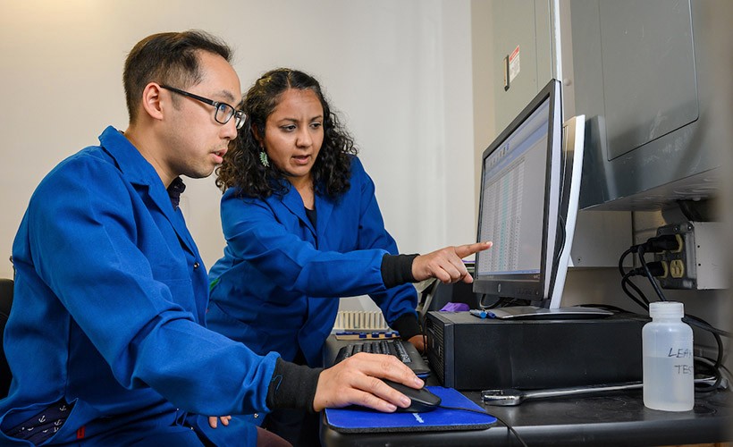 A professor and student work together at a computer.