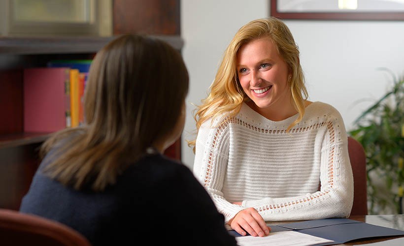 An advisor and a student sit together at a table