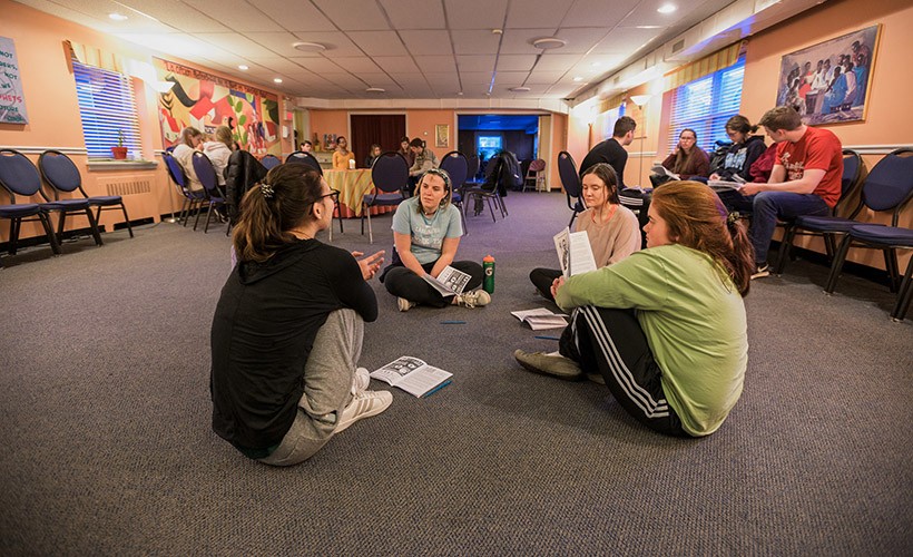 Students sit around in a circle as part of a service experience.