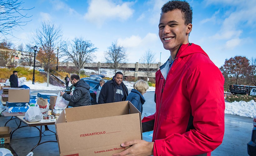A student carries a box as he does volunteer work on campus.