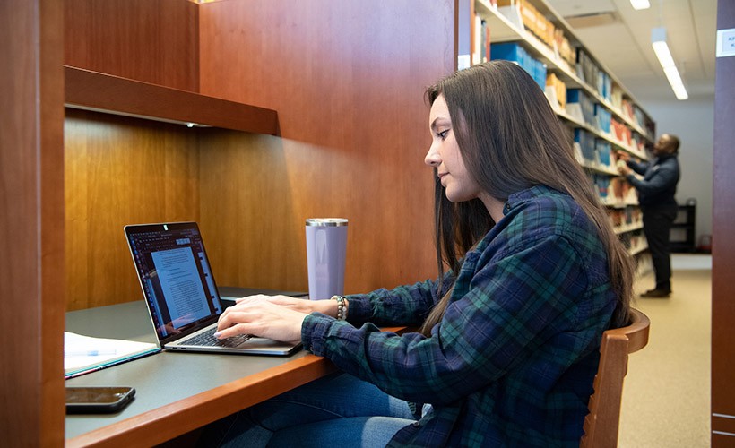 A student works at her computer in the library.
