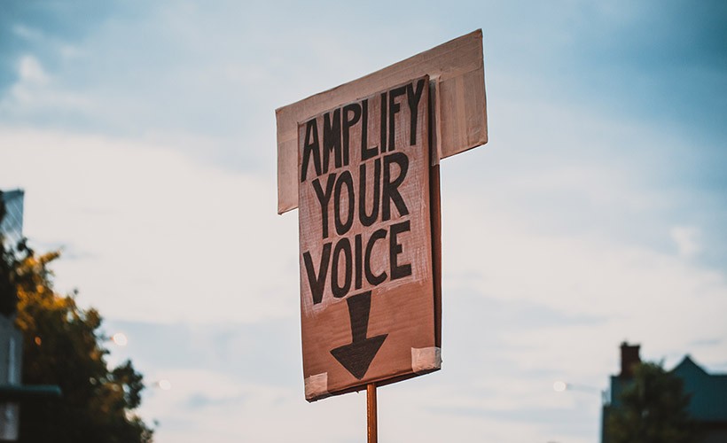 A sign that says, "Amplify your voice"