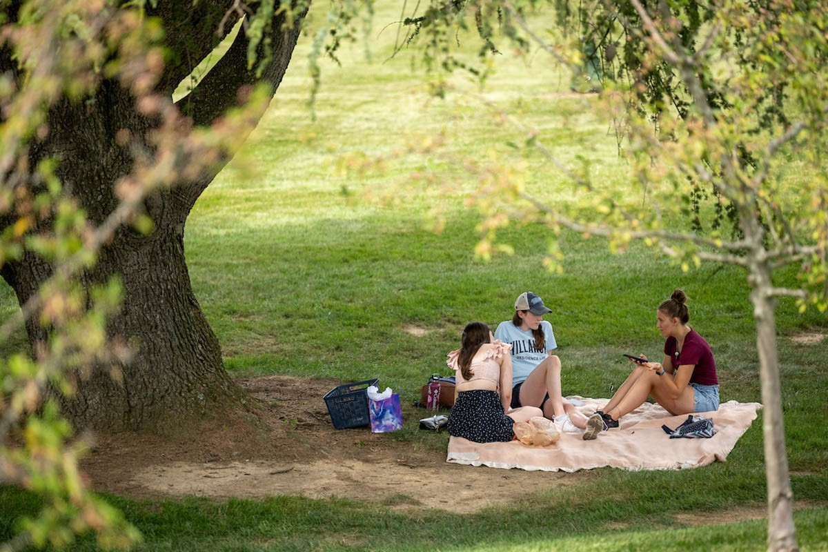 Students sitting on the grass talking on a blanket