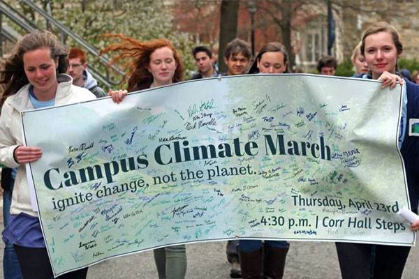 Students walking through campus holding a campus climate march banner