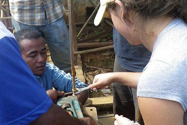 Student and CRS engineer working on a broken hand pump