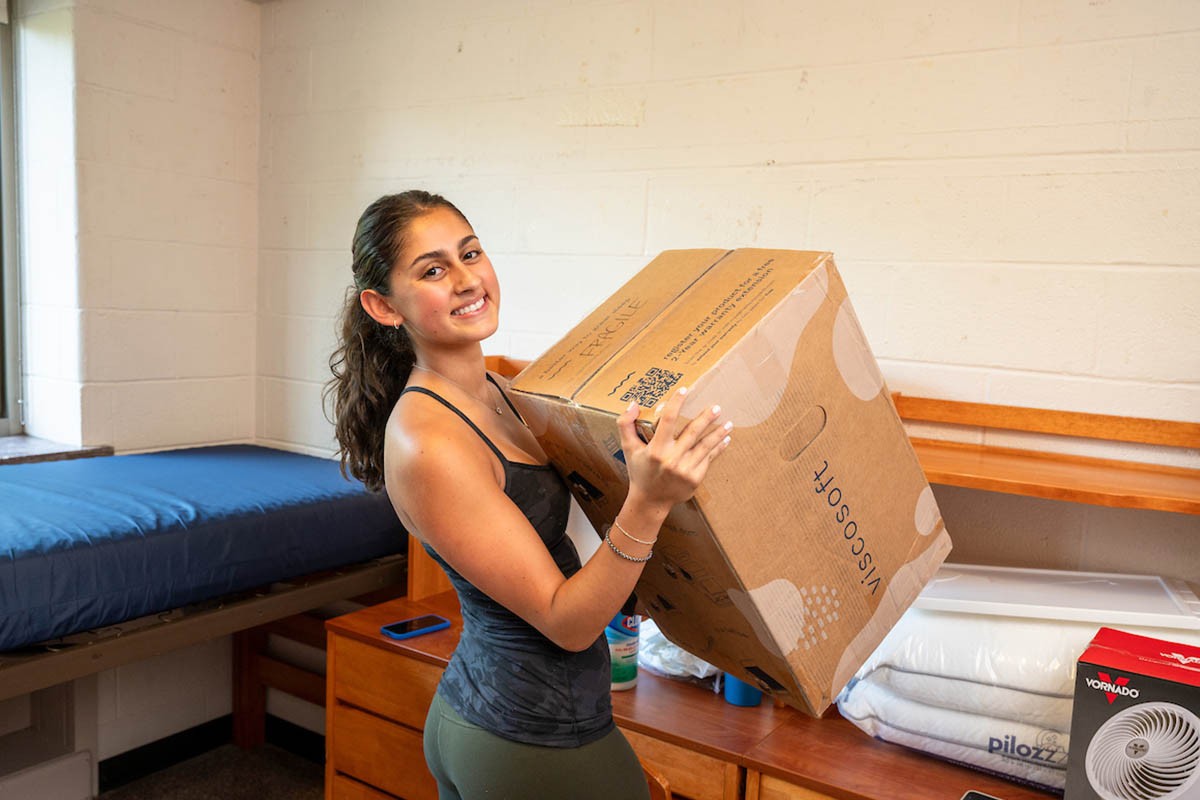 A girl smiling in her dorm as she unpacks