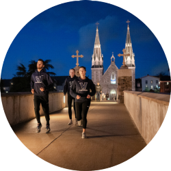 Running club members running across a bridge with a church in the background