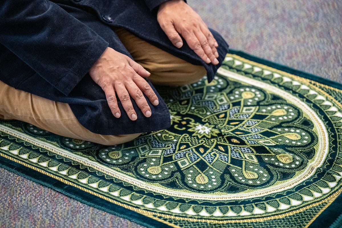 A person kneeling on a prayer mat