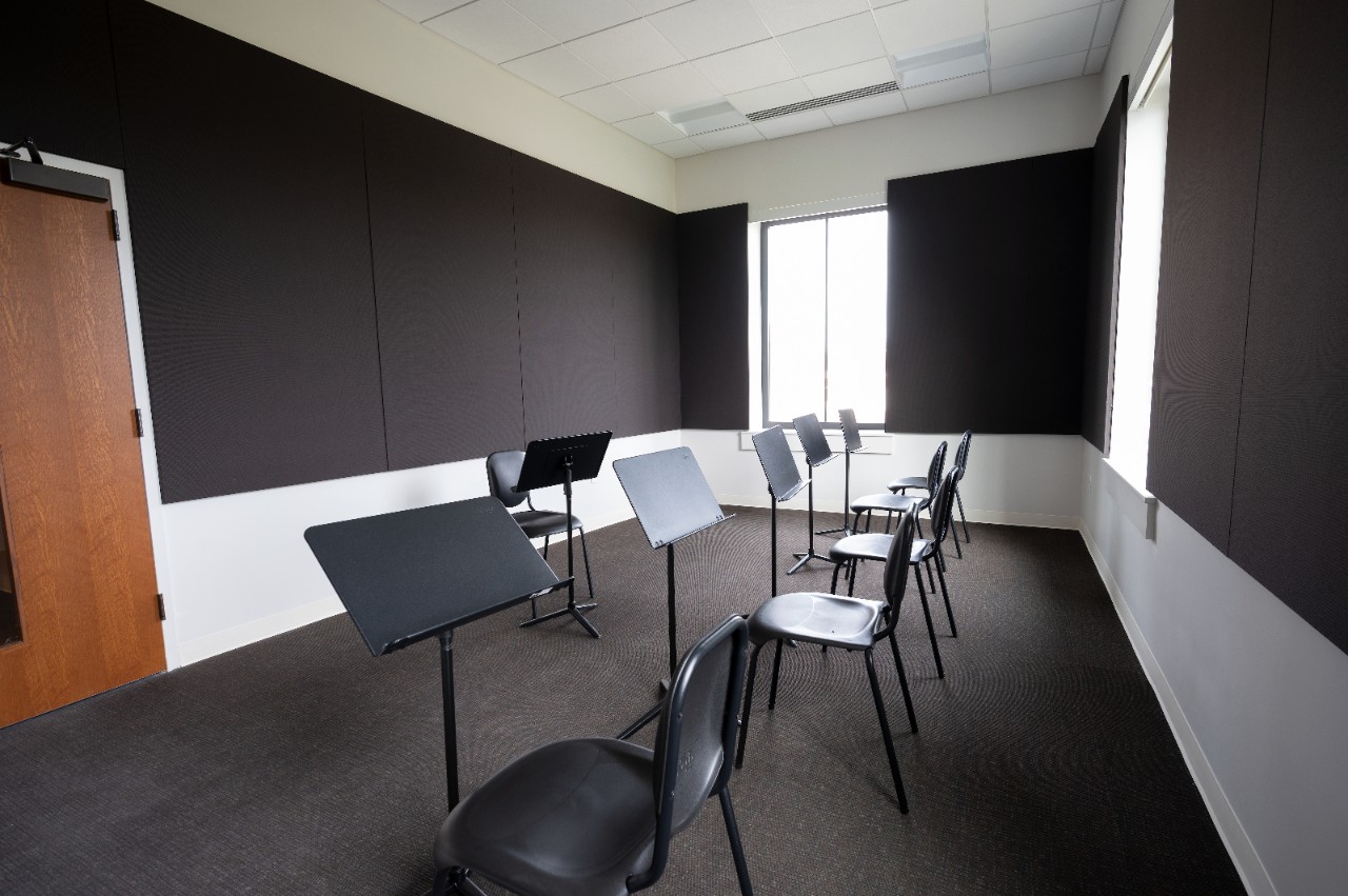 Practice room is small and soundproof with a couple chairs and music stands