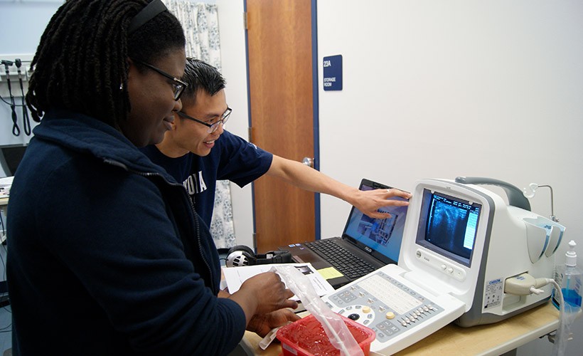 Two students work together reviewing a monitor.