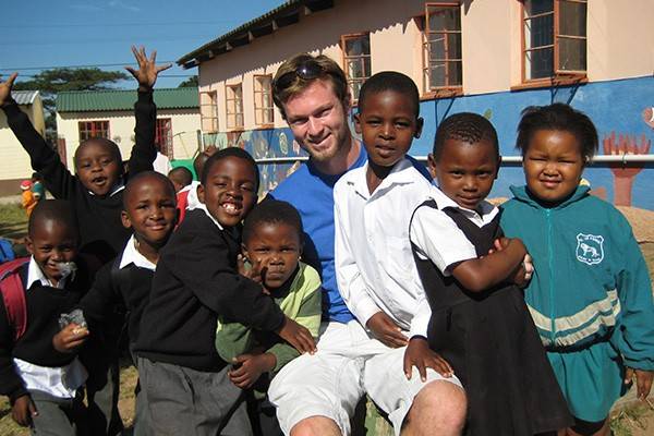 Michael Barry, graduate of the BSNExpress program stands with local children while on an international assignment.