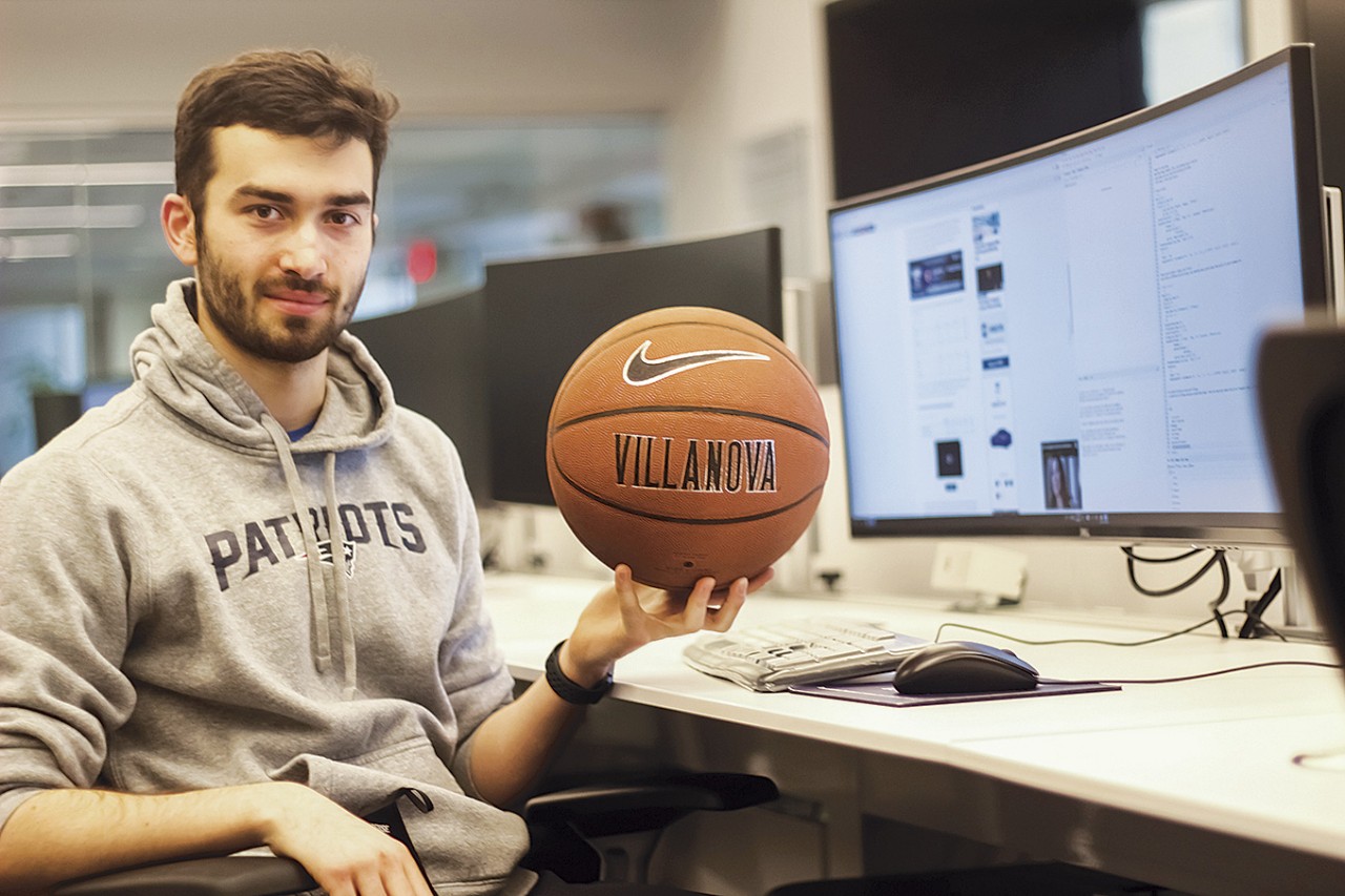 Ethan Carpenter holding a Villanova basketball in front of a computer screen