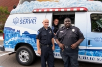 Public Safety officers smile in front of the mobile treat unit.