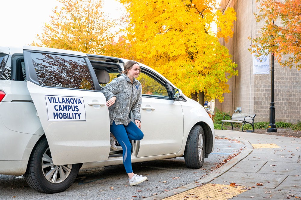 female student stepping out of campus mobility car
