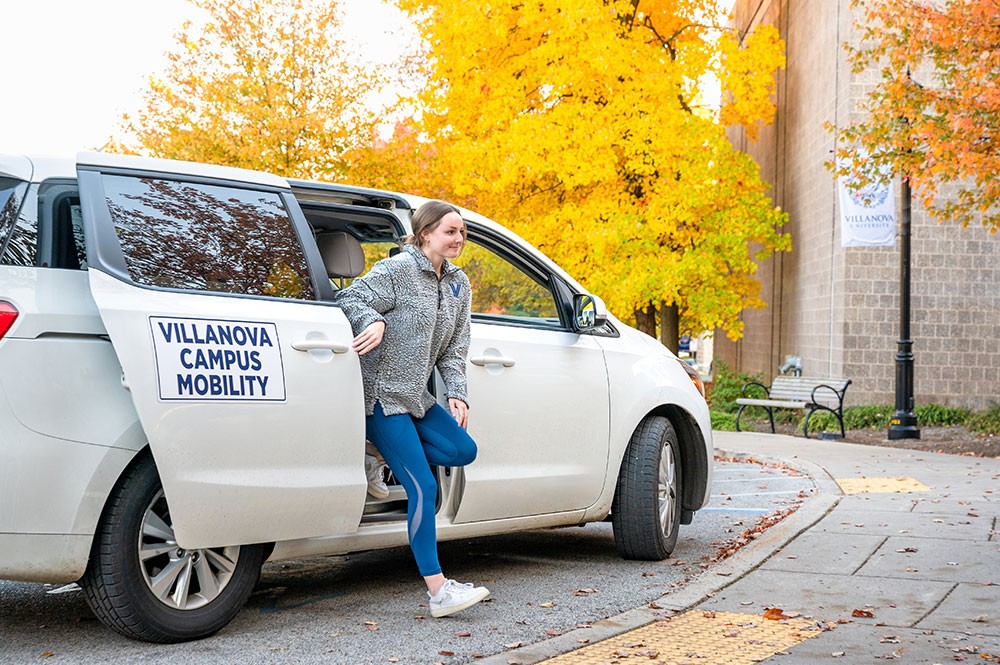 Female student stepping out of campus mobility car