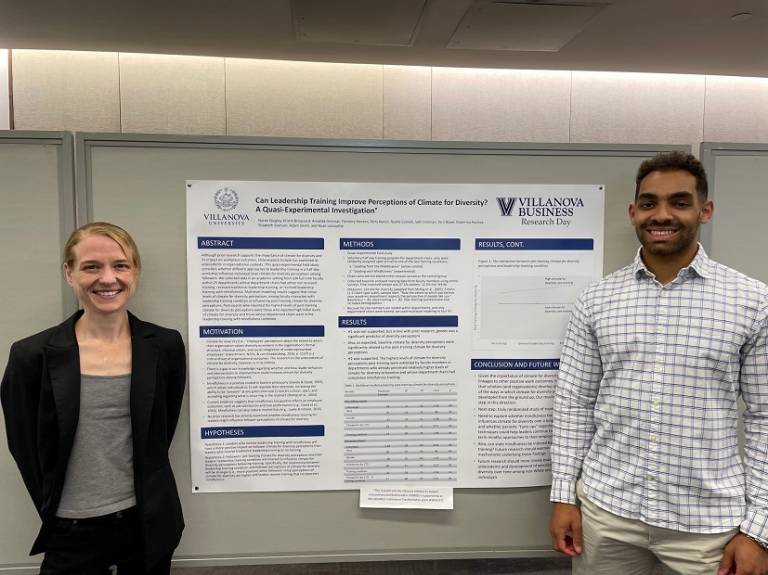 Two members of the VISIBLE research team stand with a poster at VSB Research Day 2023.