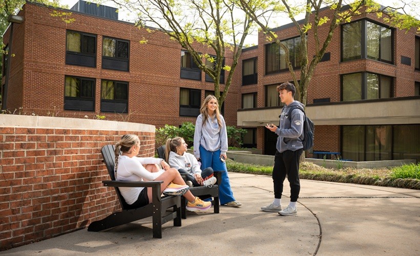 Four students talking in front of a residence hall