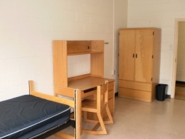 View of a bed, desk and wardrobe in a Delurey Hall room.