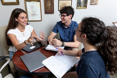students sitting around a table talking and smiling