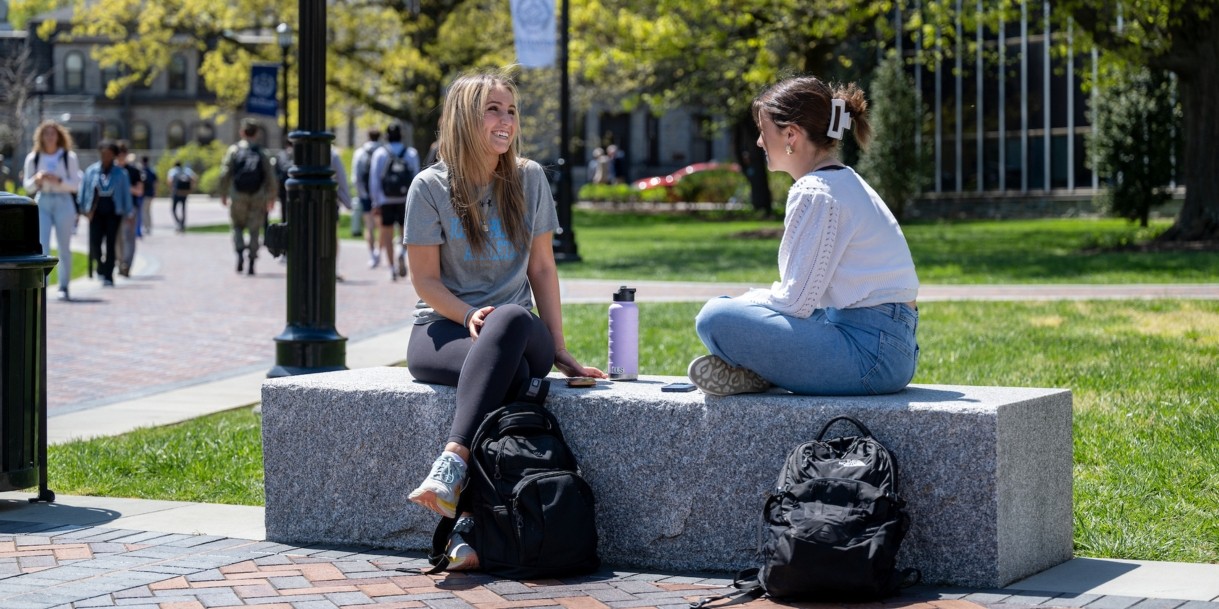 Students sitting on campus talking.