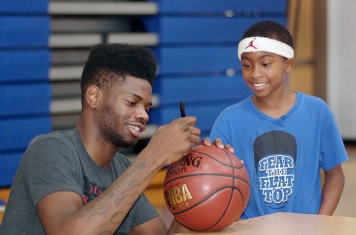 Nerlens Noel signing a basketball while a child looks on