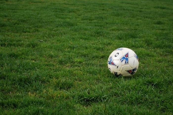 white and blue soccer ball sitting off center on a patch of green grass