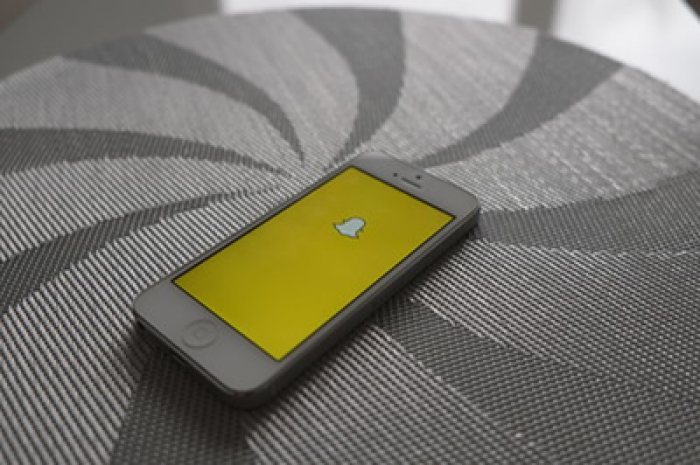 cell phone with snapchat screen open laying on a grey ottoman