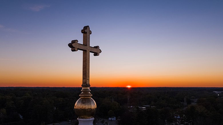 Sunrise with cross on steeple in foreground