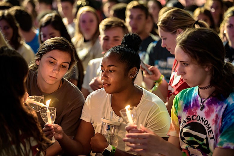 students lighting each other's candles at Mass