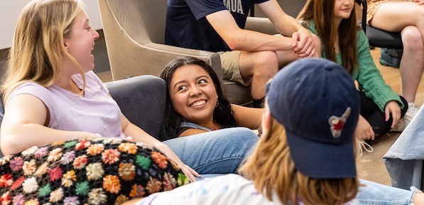 Group of students on couch speaking and smiling at one another