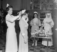 First capping of generic students, in Falvey Library, with M. Dorothy Boyle, RN, MEd., faculty member. Students are Elizabeth Curren, Cecelia DeMuro, and Sr. M. Theolinda, OSF, all class of 1957. May 8, 1955.