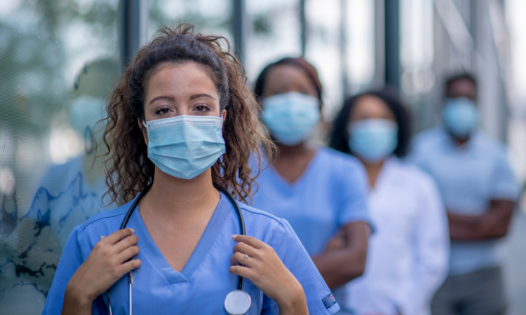 Confident female Nurse standing outside with nurses behind her