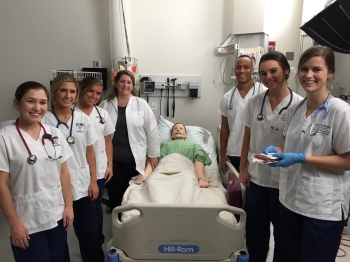 Nursing students and faculty gather around SimMan.
