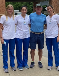 3 nursing students in scrubs stand outside with donor Fred Flynn