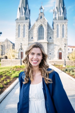 Hailey Clark in graduation gown in front of campus church