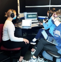 3 students record a podcast in radio station studio