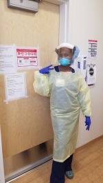 Female nurse dressed in PPE in front of hospital door.