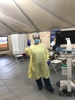 Female nurse wearing PPE in a tent.