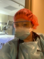 Female nurse dressed in PPE in front of hospital door.
