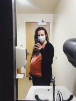 Pregnant nurse working in hospital with a mask covering her face.