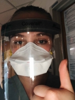 Female nurse wearing shield and mask over her face.