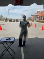 Female nurse stands outside a hospital while wearing PPE.