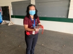 Female nurse carrying supplies with a mask covering her mouth and nose.