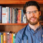 Male nurse standing in front of bookcase.