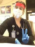 Female nurse wearing shield and mask over her face.