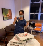 Female nurse taking a break and eating pizzas donated by a fellow Villanova alum.