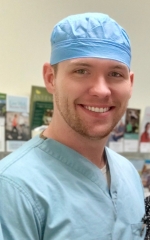 Male nurse in blue scrubs and a hat.
